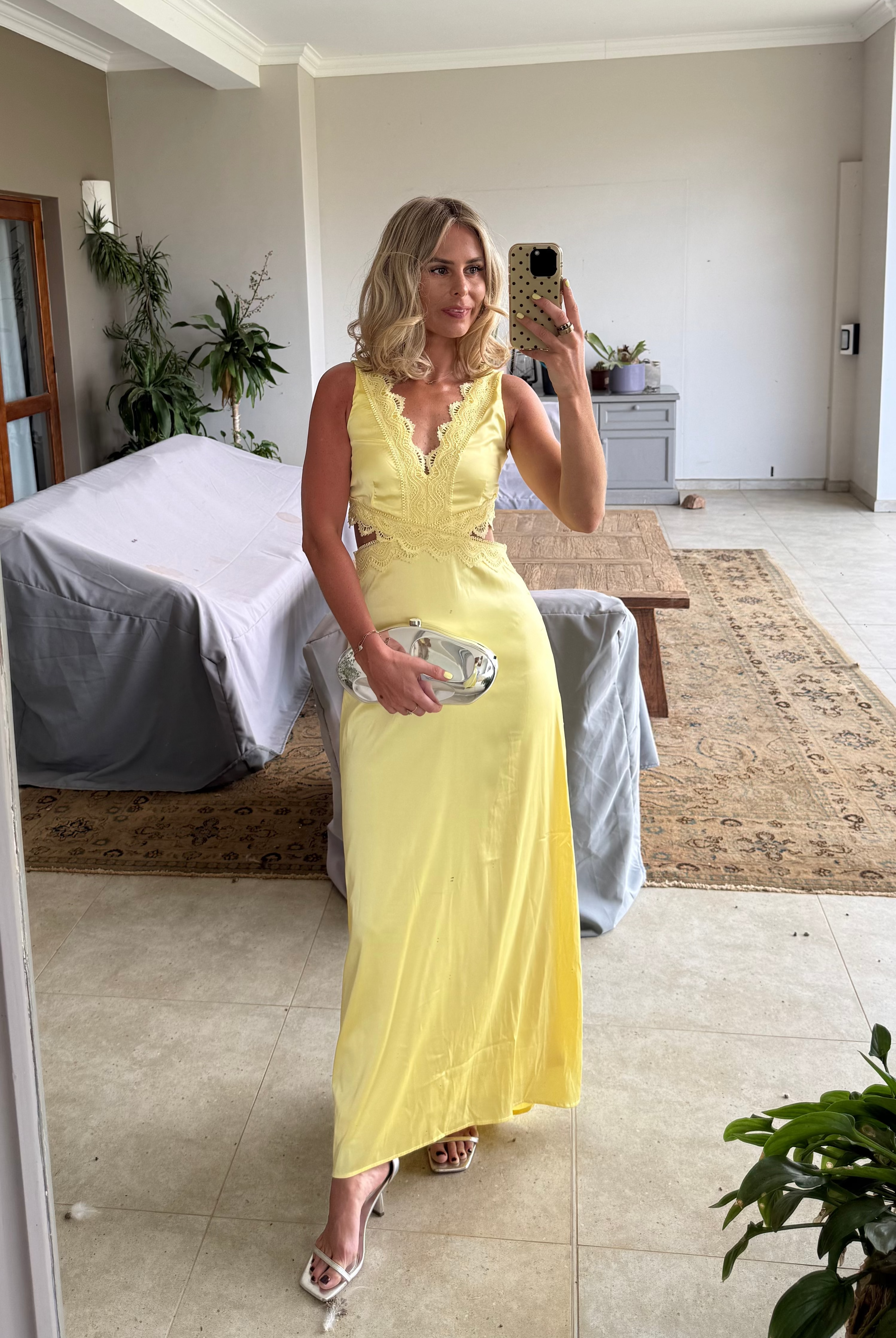 Girl wearing yellow wedding guest dress with silver clutch bag.