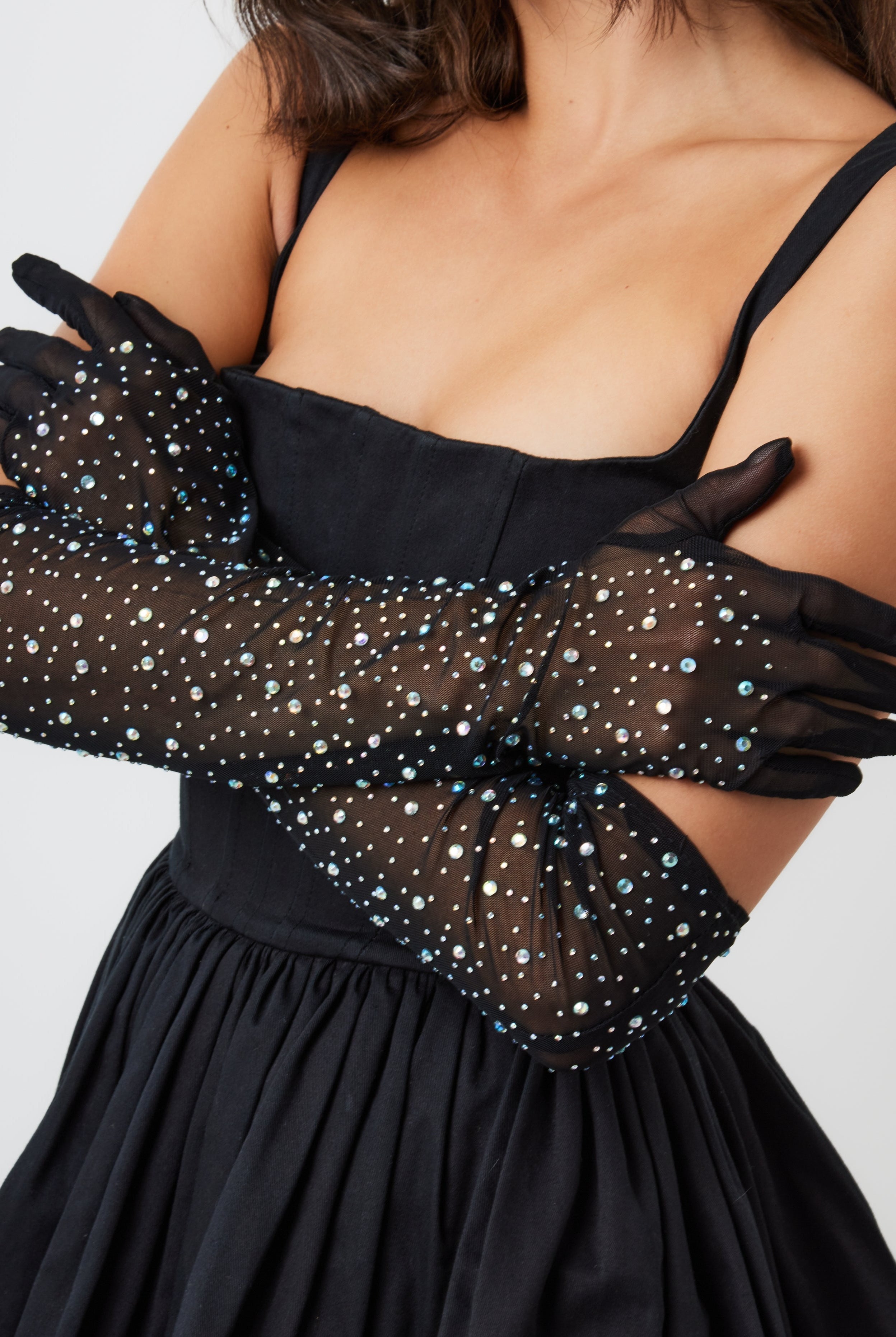 A woman wearing black over-the-elbow mesh gloves embellished with rhinestones.