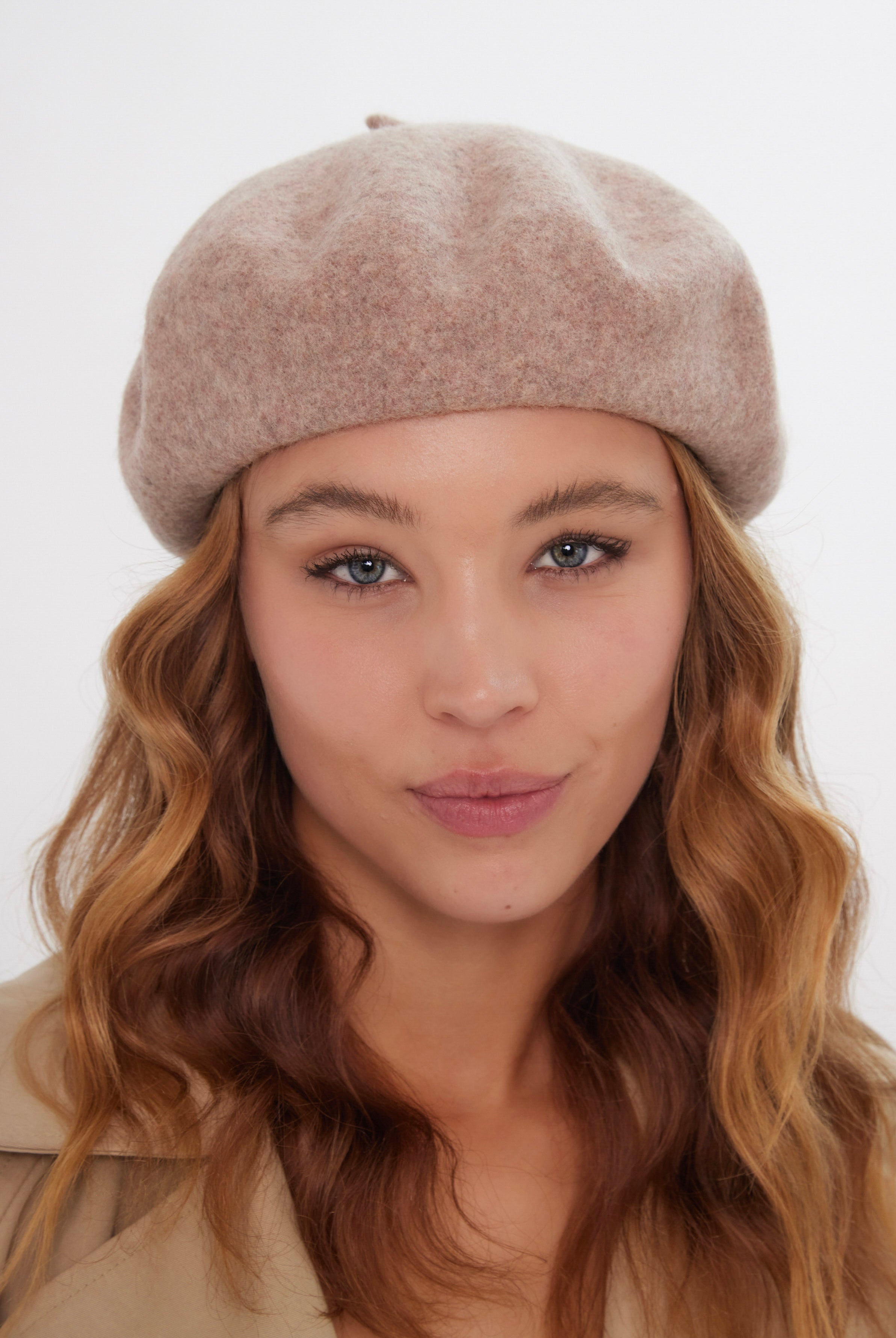 Woman wearing a beige beret against a white background