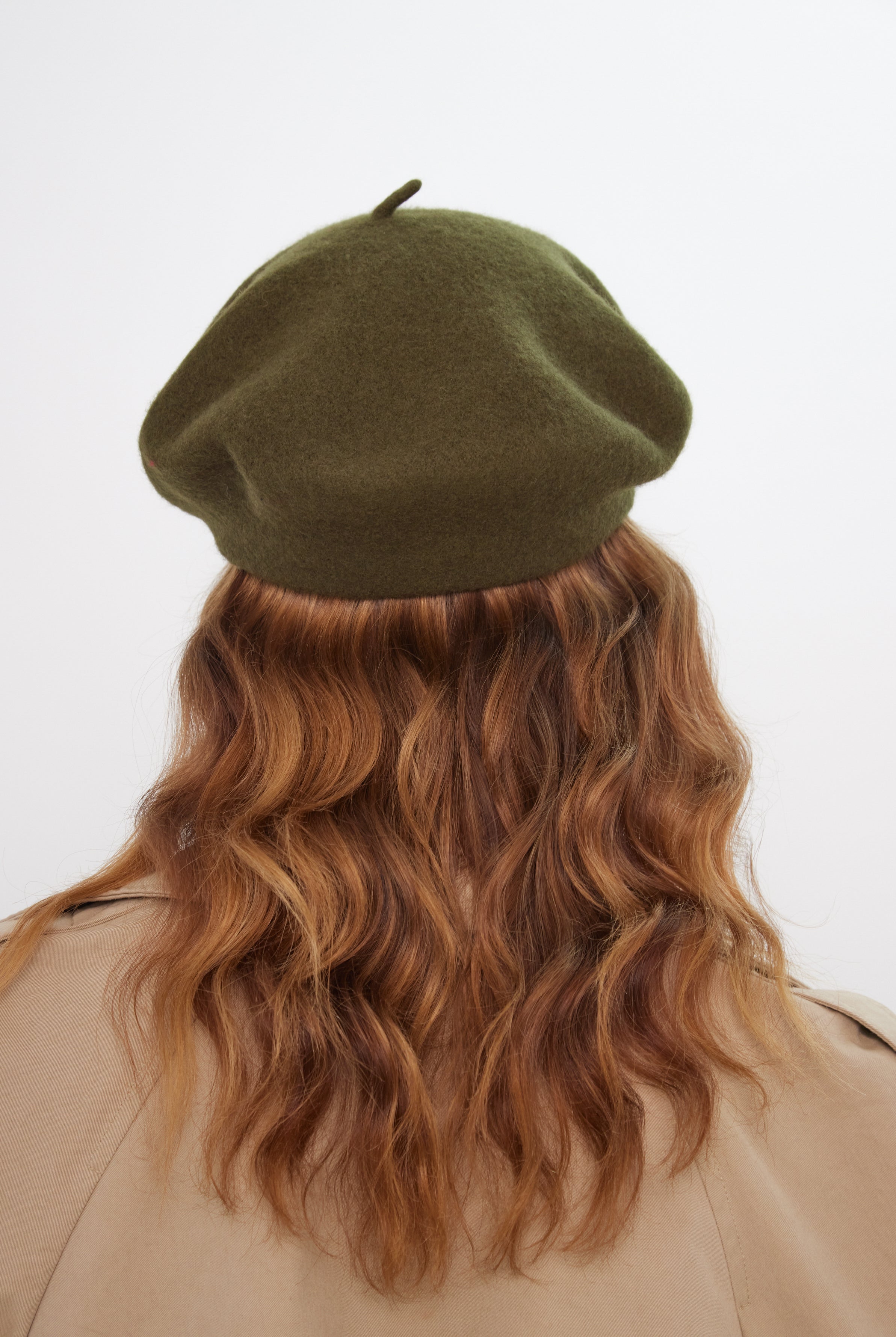 Person wearing a green beret with wavy hair on a white background