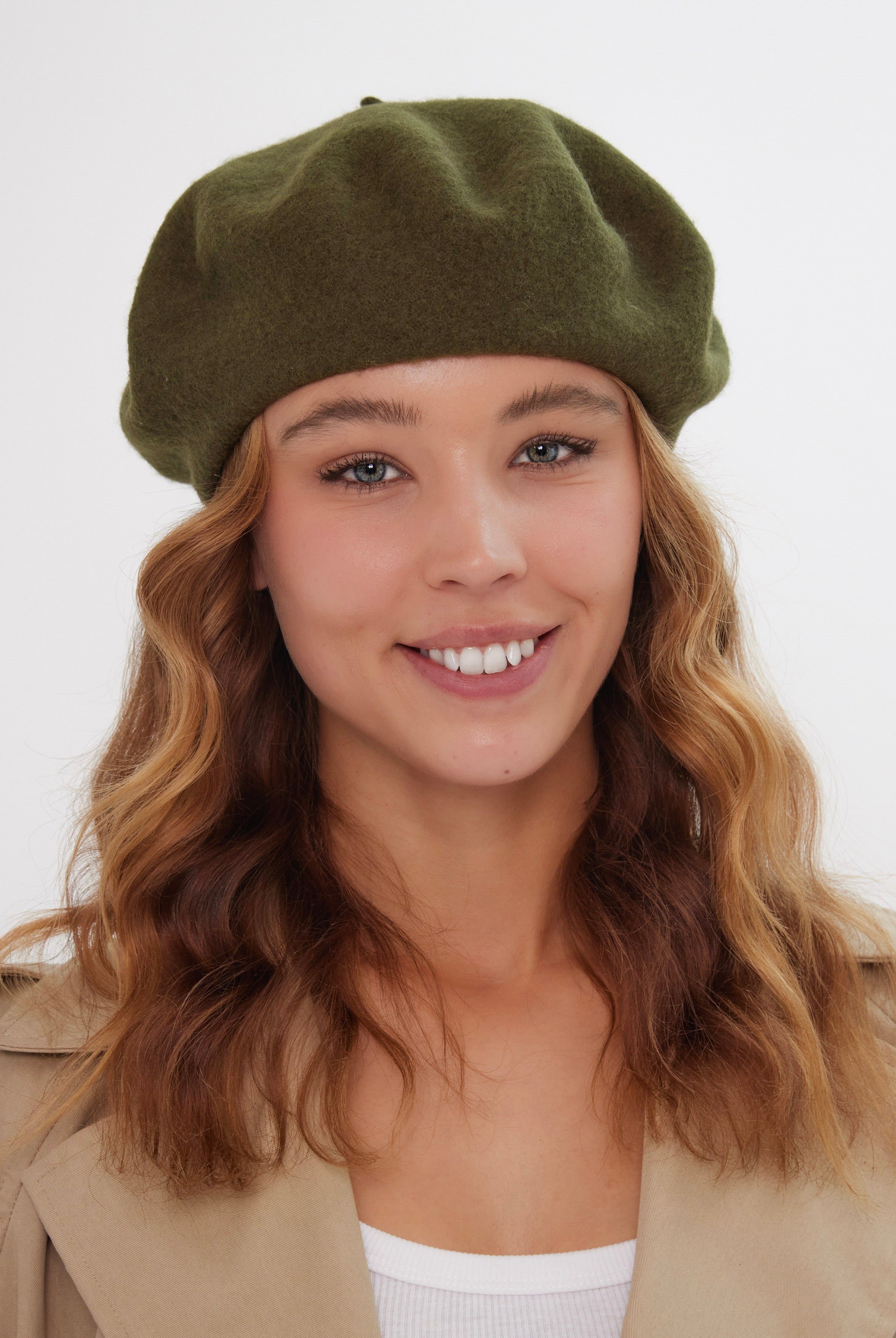 Woman wearing a green beret against a white background