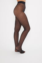 Black patterned tights worn by a person on a white background