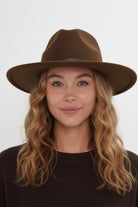 Woman wearing a brown fedora hat against a white background