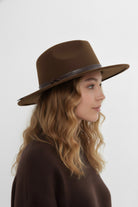 Woman wearing a brown fedora hat against a white background