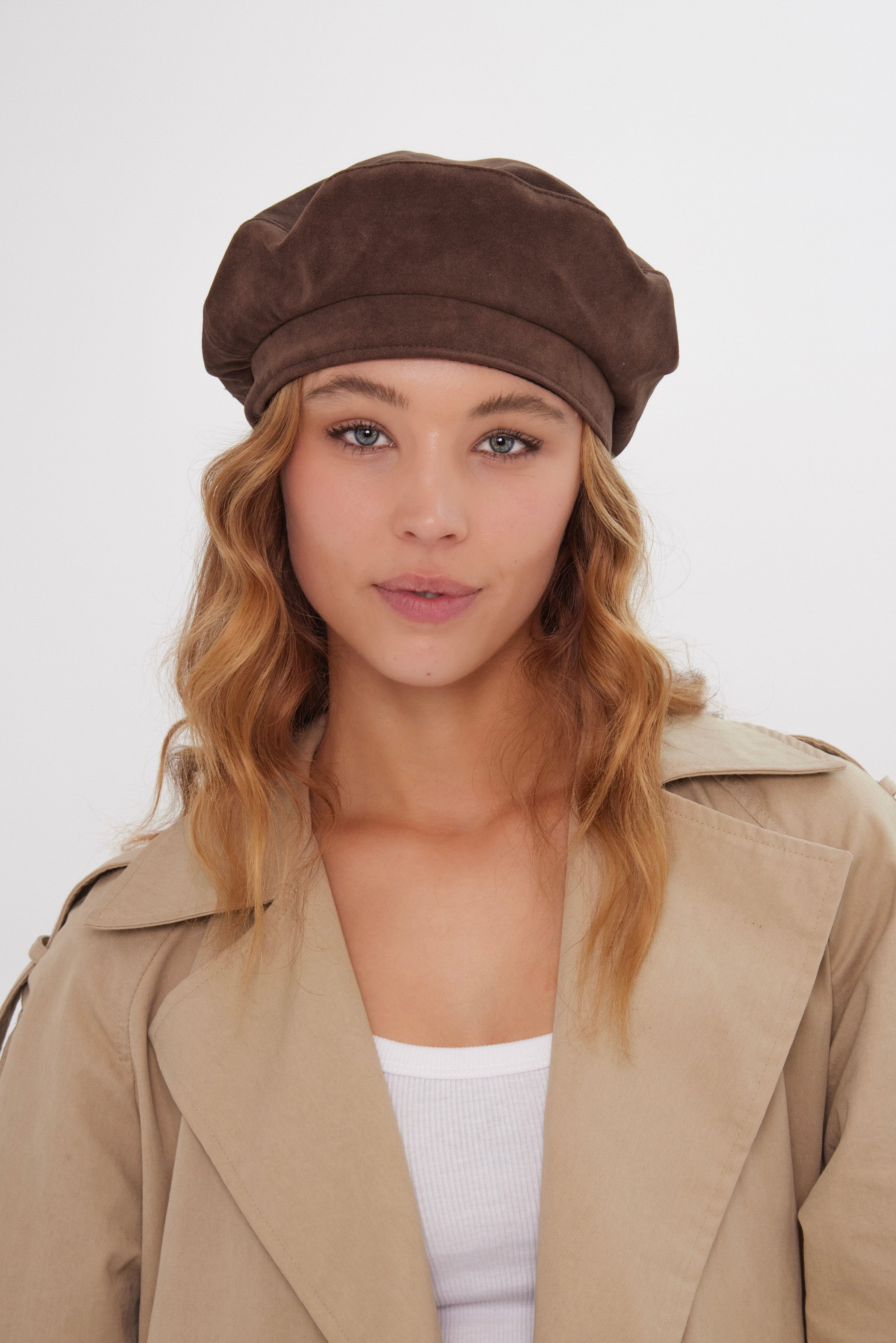 Woman wearing a brown beret and beige trench coat against a white background
