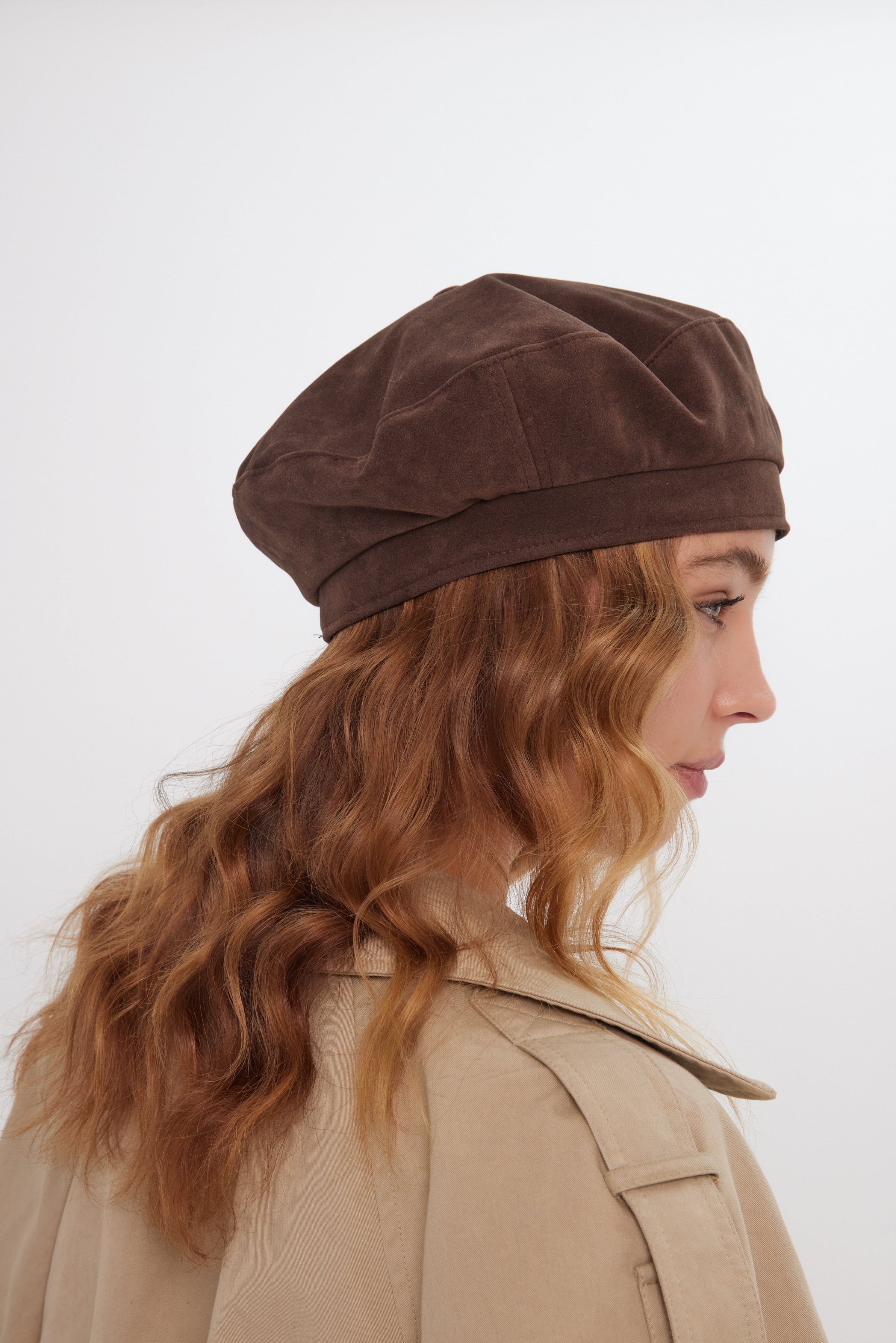 Woman wearing a brown beret and beige coat on a white background
