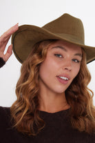 Woman wearing a green cowboy hat against a white background