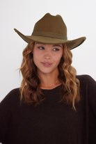 Woman wearing a green cowboy hat against a white background