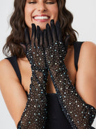 A woman wearing black over-the-elbow mesh gloves embellished with rhinestones.