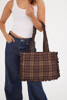 Person holding a plaid burgundy tot bag against a white background
