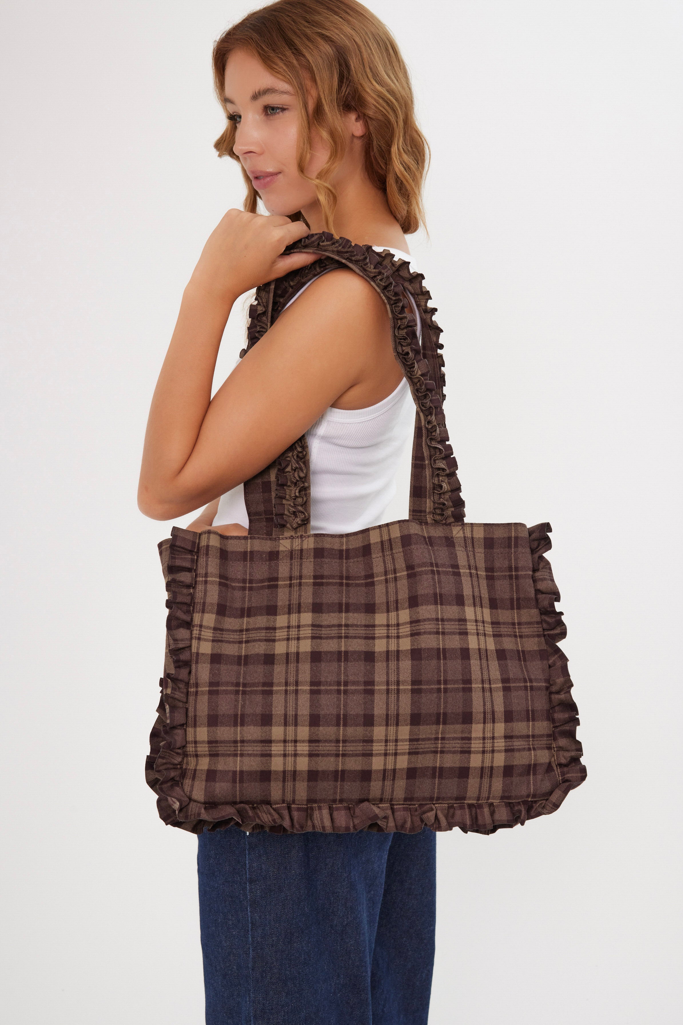 Woman holding a brown plaid check burgundy bag against a white background
