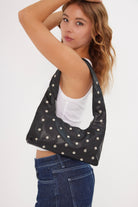 Woman wearing a black studded top with a white background