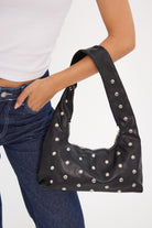 Black studded handbag held by a woman