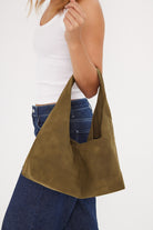 Person holding a green handbag against a white background