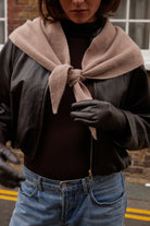 Person wearing a brown jacket, brown gloves, and a beige scarf 