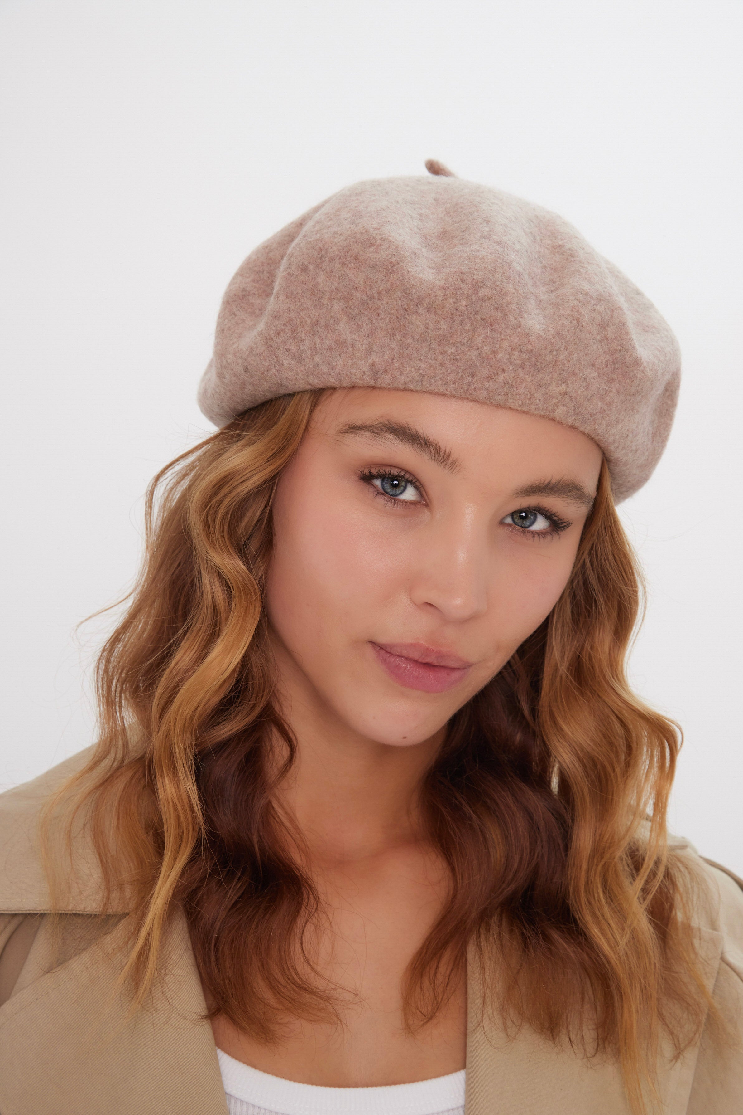 Woman wearing a beige beret against a white background