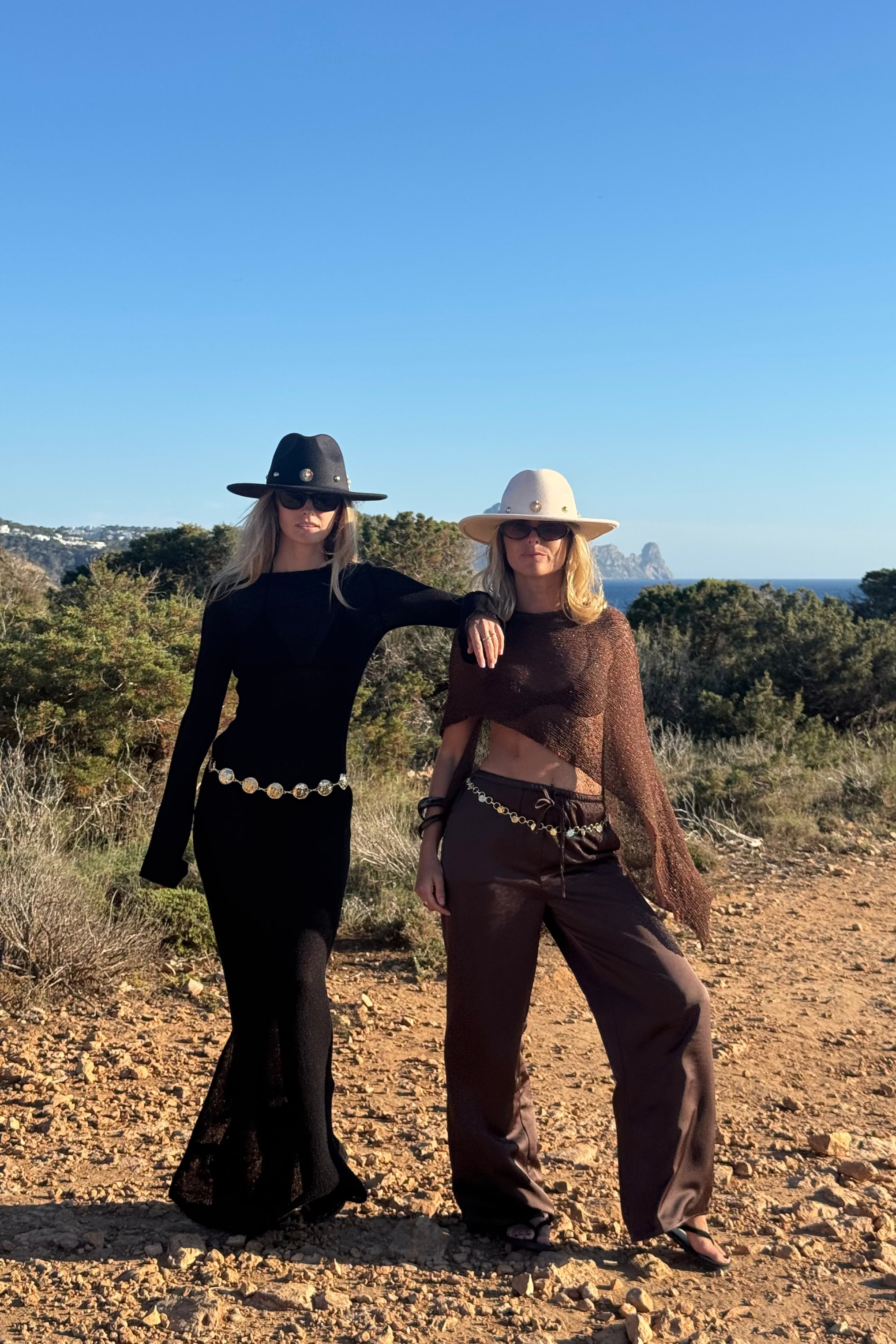 Two people posing outdoors in a natural setting with clear blue sky.