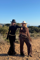 Two people posing outdoors in a natural setting with clear blue sky.