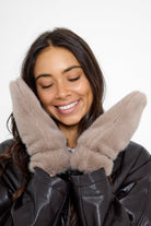 Model wearing fluffy Fur Mittens in Taupe and a brown leather jacket and jeans